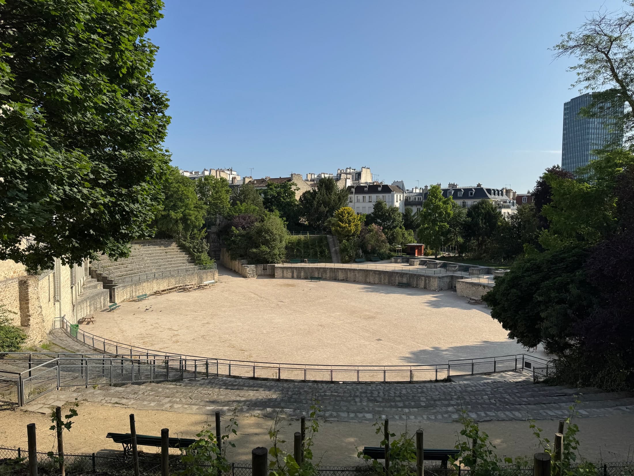 The Roman arena at Arènes de Lutèce, surrounded by trees and Paris rooftops