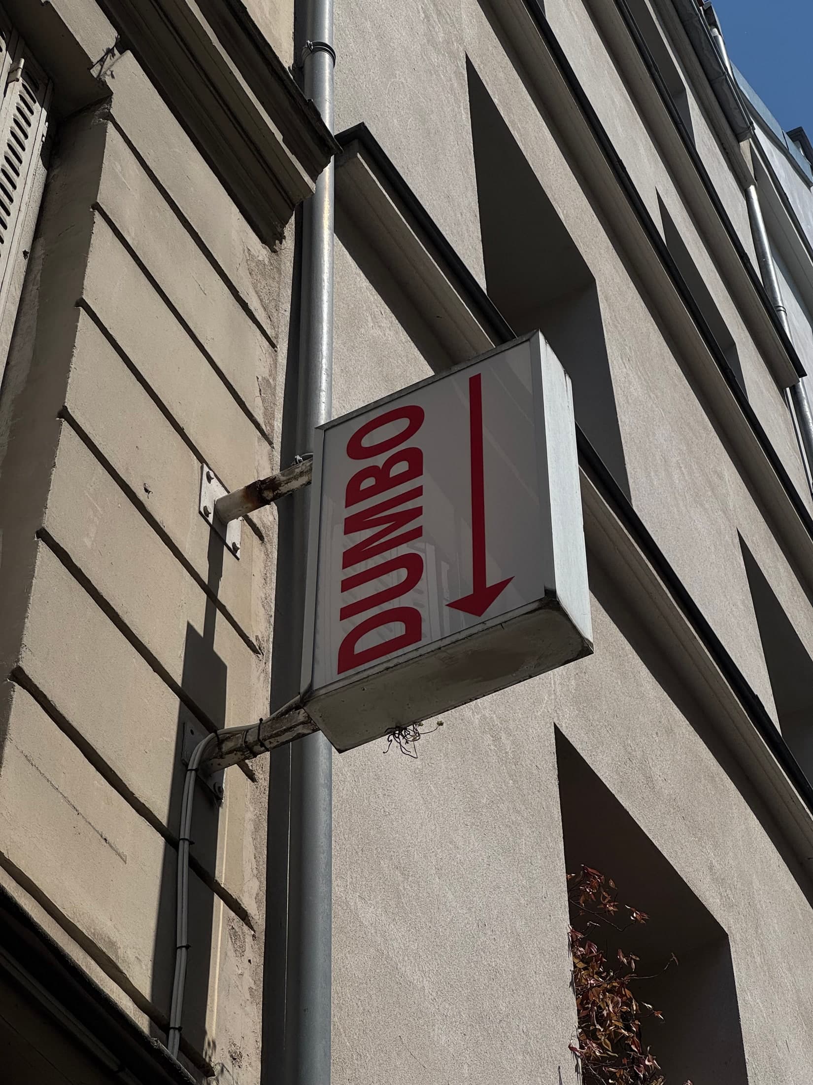 Enseigne rouge DUMBO et flèche sur une façade du Marais